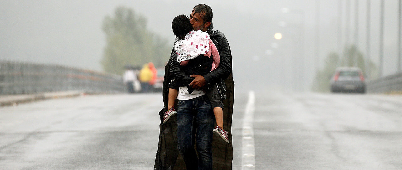 Un refugiado sirio besa a su hija mientras camina bajo la lluvia hacia la frontera de Grecia con Macedonia, cerca del pueblo griego de Idomeni, 10...
