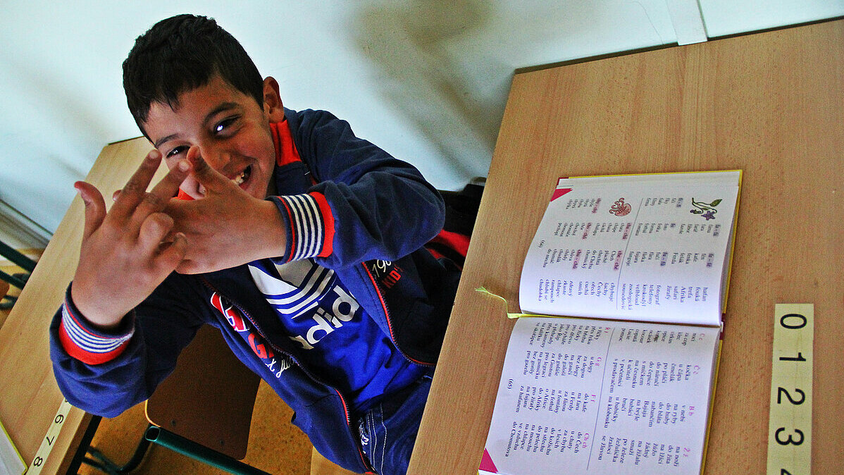 Estudiante gitano saludando en el aula