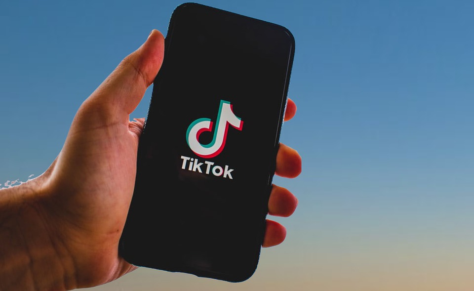 Mano sujetando un teléfono móvil en el que se ve el símbolo de TikTok ©Nikuga/Pixabay