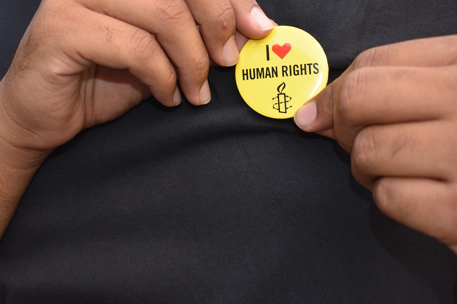 [Translate to eus:] Manos sosteniendo una chapa en la que pone 'I love human rights'