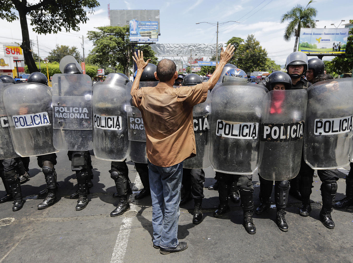 Un home fronte a una liña de policías antidisturbios que bloquean unha rúa durante unha protesta contra o goberno do presidente nicaraguano Daniel...