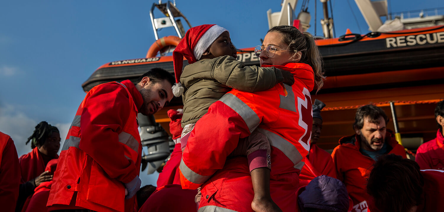 [Translate to gal:] Un niño migrante es desembarcado del barco de rescate de la ONG española Proactiva Open Arms en el puerto de Crinavis en...