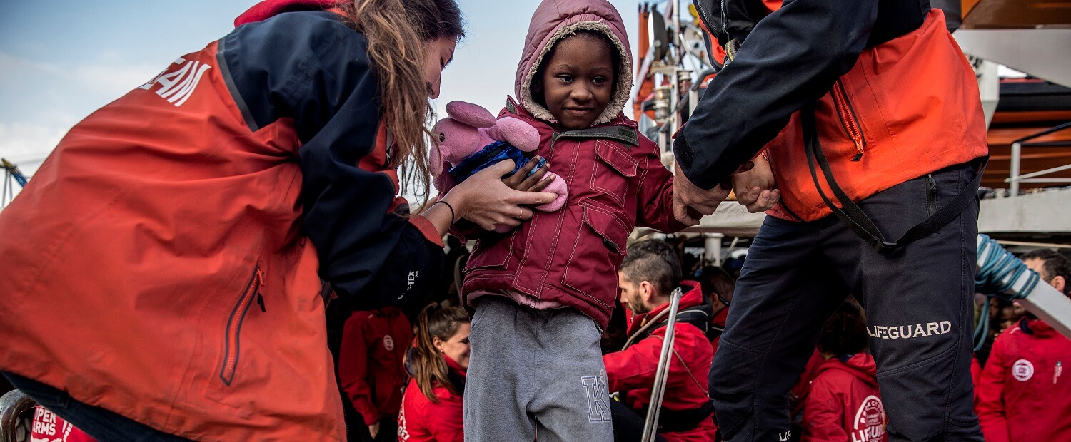 Un niño migrante es ayudado desde el barco de rescate de la ONG española Proactiva Open Arms, tras ser rescatado el 21 de diciembre en el Mar...