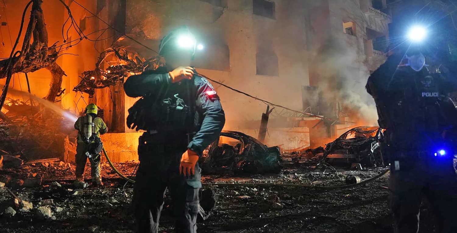 Personal de emergencia y soldados israelíes buscan y rescatan personas entre escombros humeantes tras un ataque con misiles.