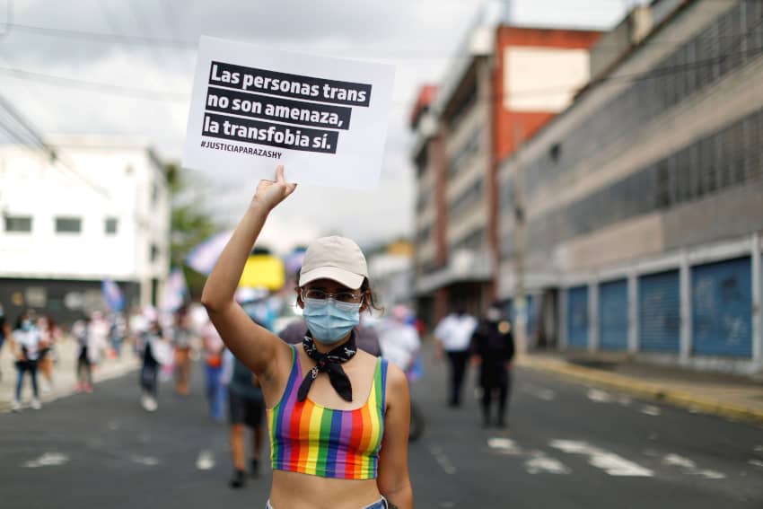 Una mujer participa en una protesta con un cartel que dice: "Las personas trans no son una amenaza, la transfobia, sí" para conmemorar el Día Internacional contra la Homofobia, la Transfobia y la Bifobia