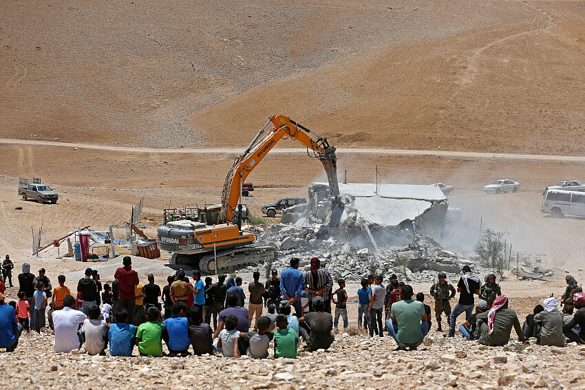 Residentes observan cómo una excavadora israelí derriba una casa palestina