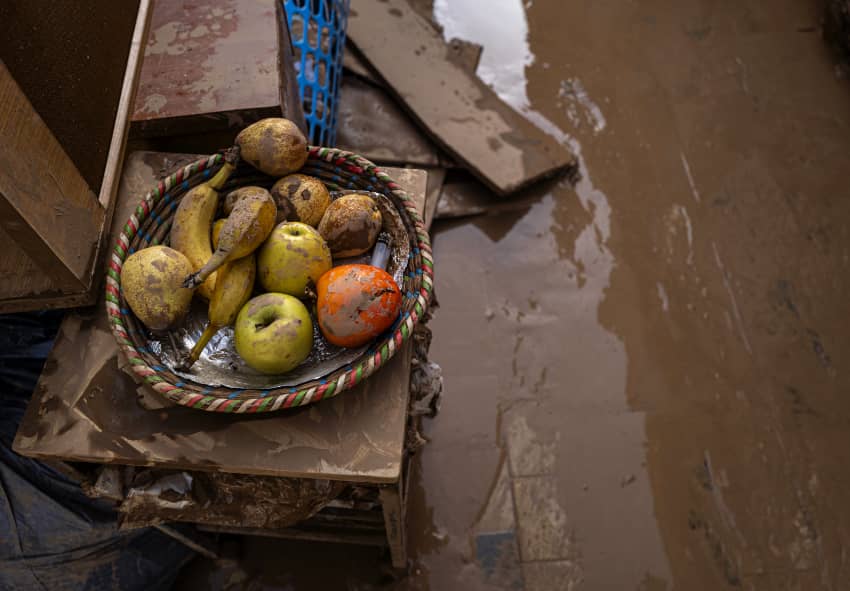 Imagen de un cuenco con fruta dañada en medio de una habitación afectada por las inundaciones