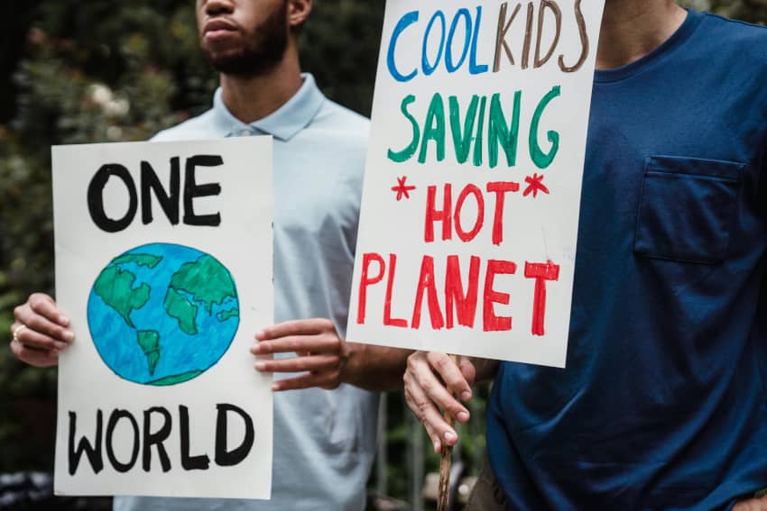 Dos jóvenes sostienen carteles sobre la protección del planeta en una acción de concienciación sobre cambio climático.